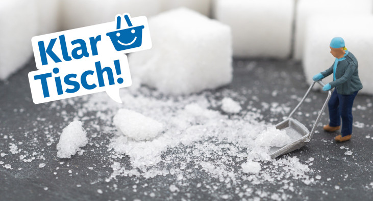 Miniaturperson mit Schneeschieber vor Zuckerwürfeln
